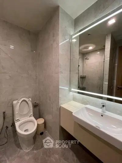 Modern bathroom with marble tiles and illuminated mirror