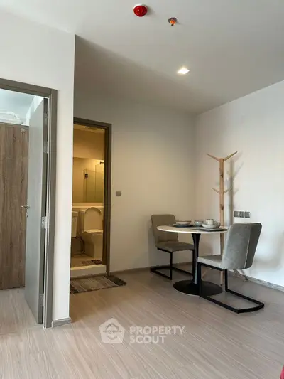 Modern apartment dining area with cozy seating and bathroom access, ideal for urban living.