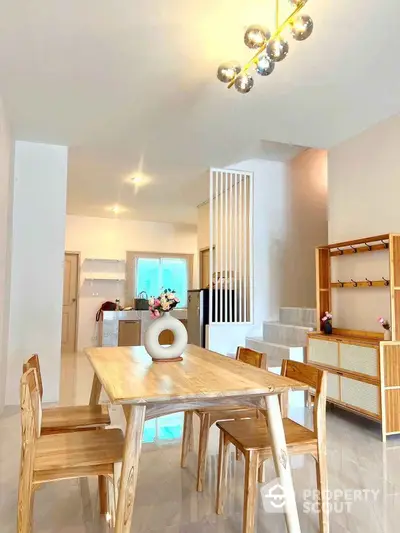 Modern dining area with wooden furniture and open kitchen layout in a bright home interior.