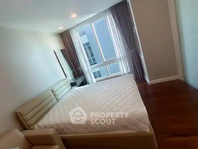Spacious bedroom with large window and modern furnishings in a stylish apartment.