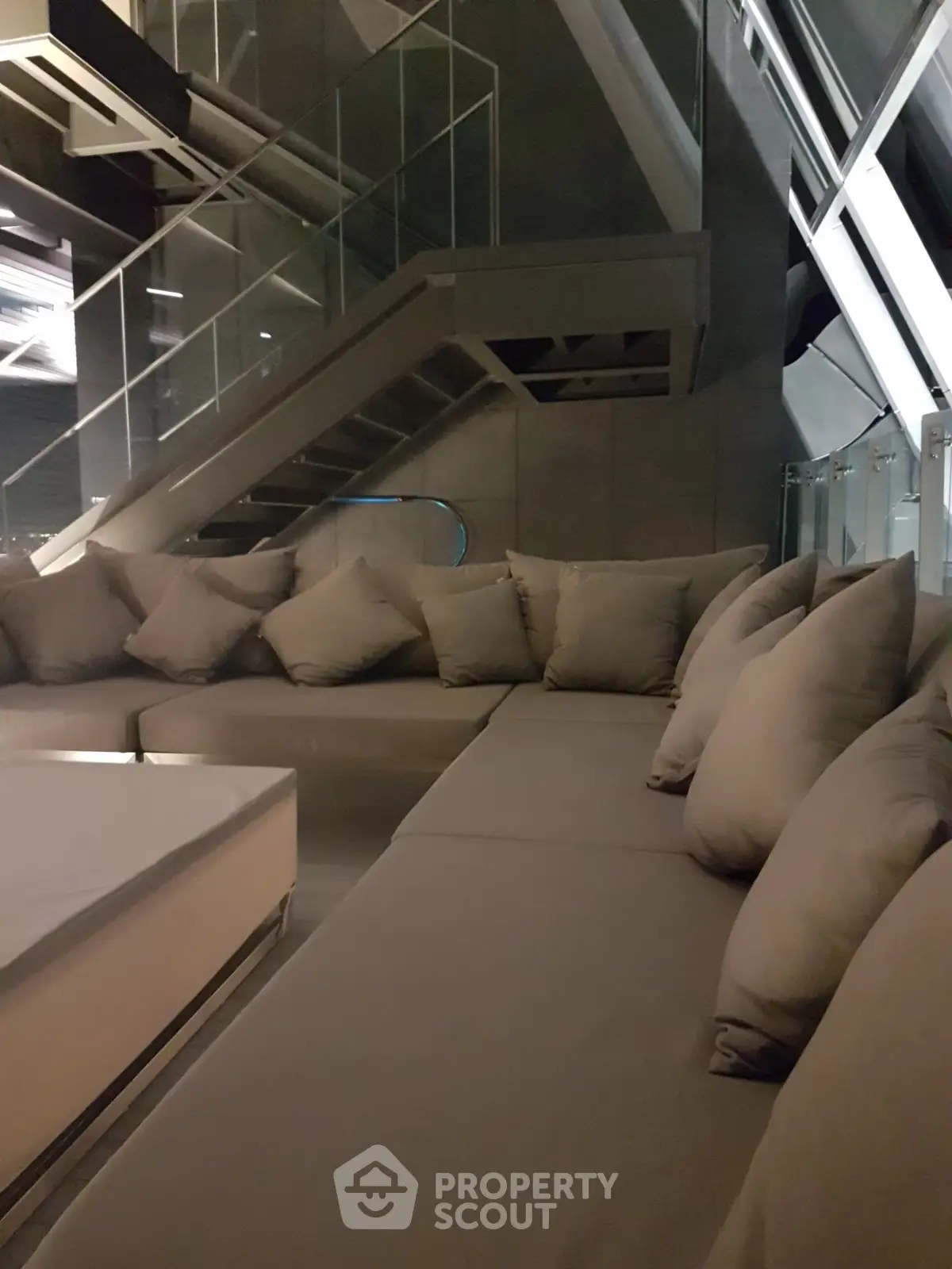 Luxurious modern living room with plush sectional sofa and sleek staircase, perfect for stylish urban living.