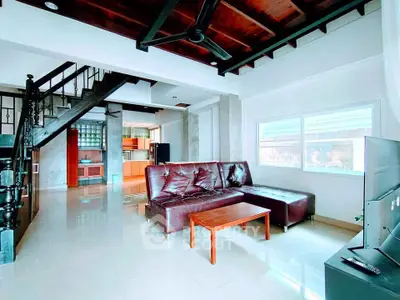 Spacious modern living room with leather sofa and open kitchen layout