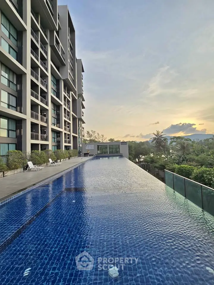 Luxurious apartment building with stunning infinity pool and sunset view.