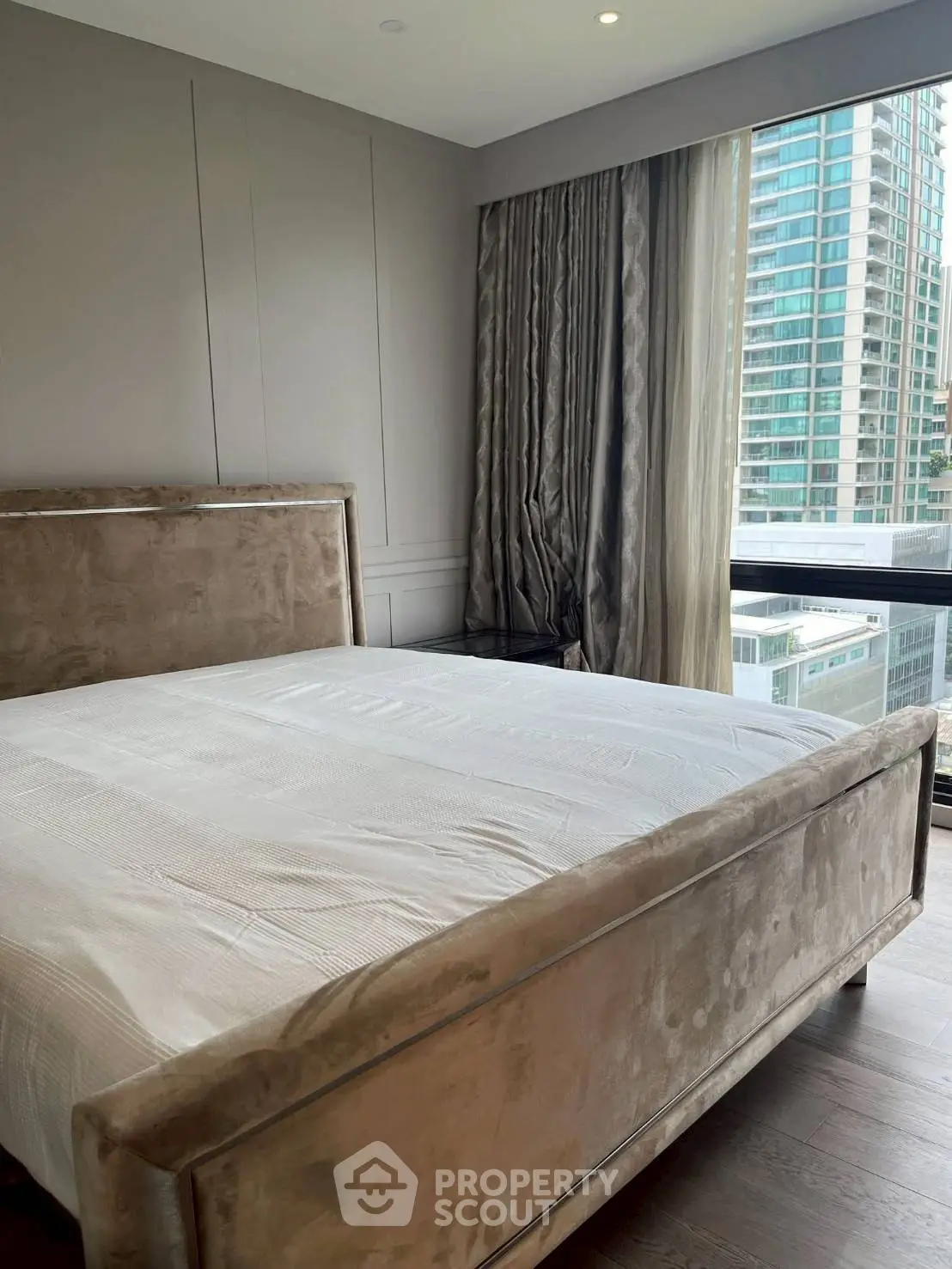 Luxurious bedroom with plush bed and city view in modern high-rise apartment.
