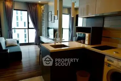 Modern apartment interior with open kitchen and living area, featuring sleek appliances and large windows.