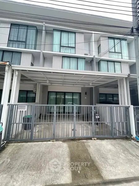 Modern townhouse exterior with gated driveway and large windows