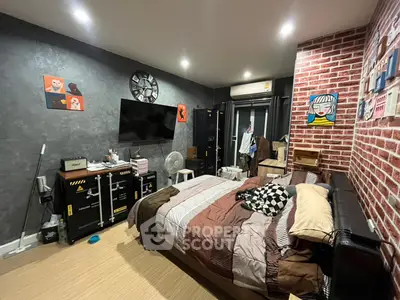 Stylish bedroom with modern decor and exposed brick wall, featuring a cozy bed and wall-mounted TV.