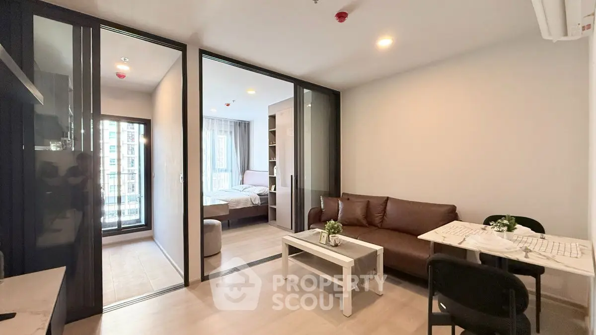 Modern apartment interior with living room and bedroom, featuring sleek furniture and natural light.