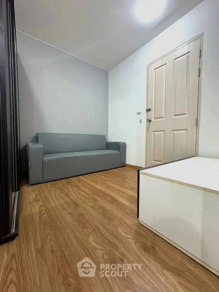 Cozy small living room with modern gray sofa and wooden flooring