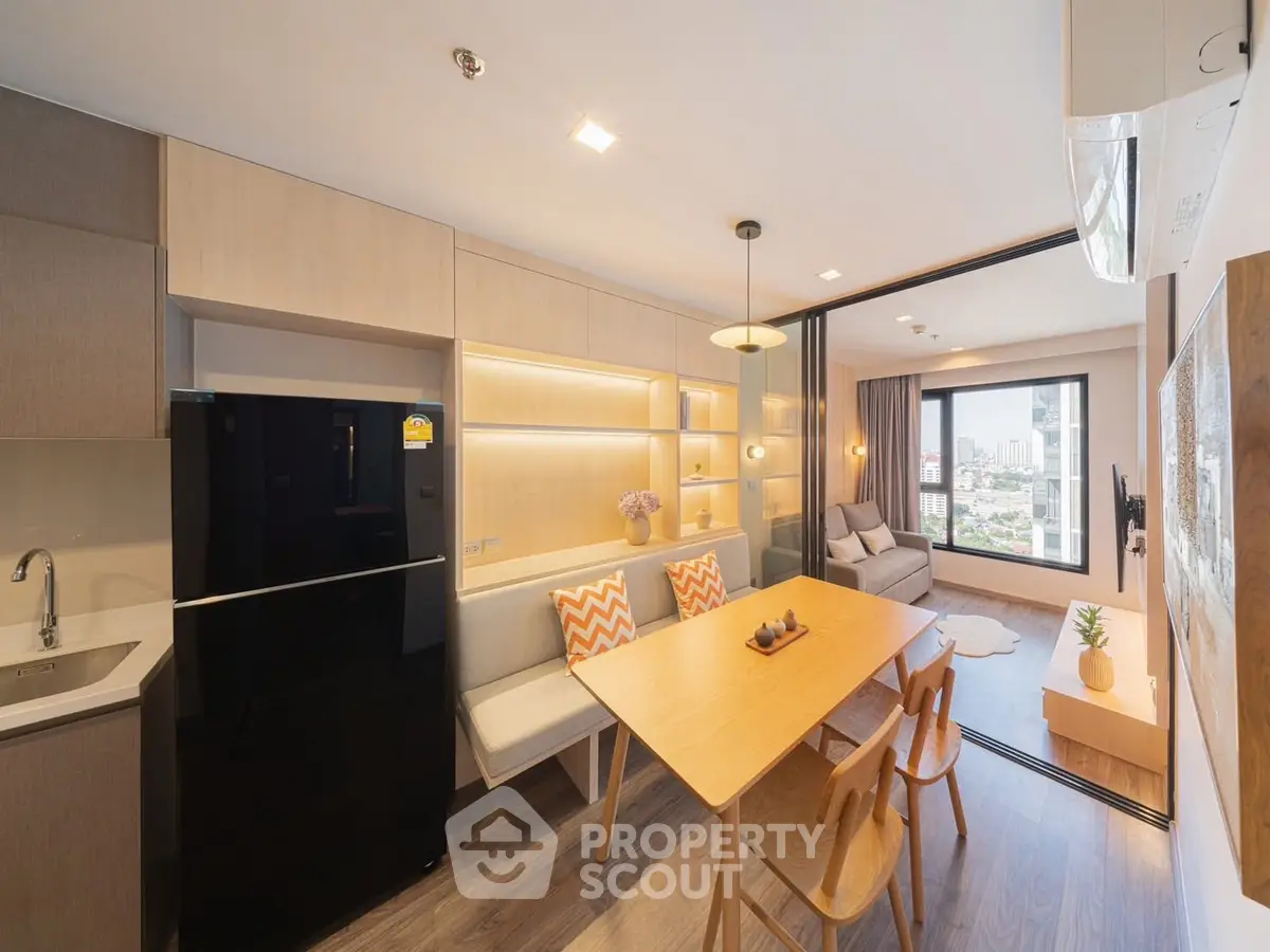 Modern open-plan kitchen and living area with city view, sleek furniture, and warm lighting.