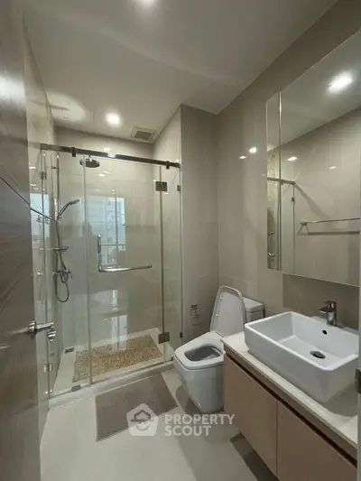 Modern bathroom with glass shower, sleek fixtures, and elegant design.