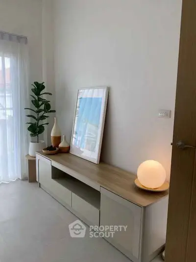 Modern living room with stylish decor and natural light, featuring a sleek console table and elegant lighting.