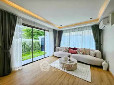 Spacious living room with modern decor and large windows overlooking a lush garden.