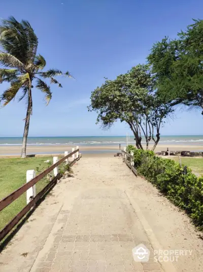 Stunning beachfront view with lush greenery and clear blue skies, perfect for serene coastal living.