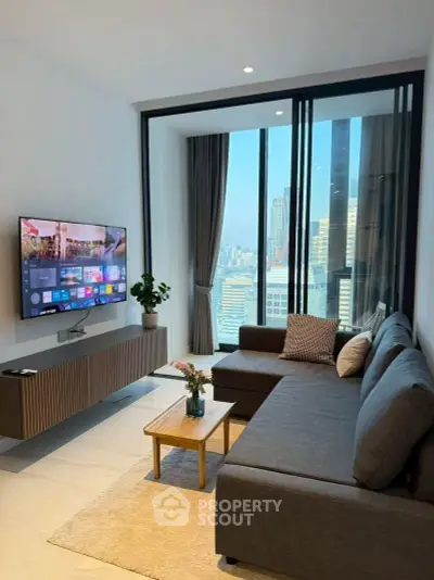 Modern living room with city view, sleek furniture, and wall-mounted TV in a high-rise apartment.
