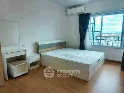 Spacious bedroom with large window and city view, featuring modern furniture and air conditioning.