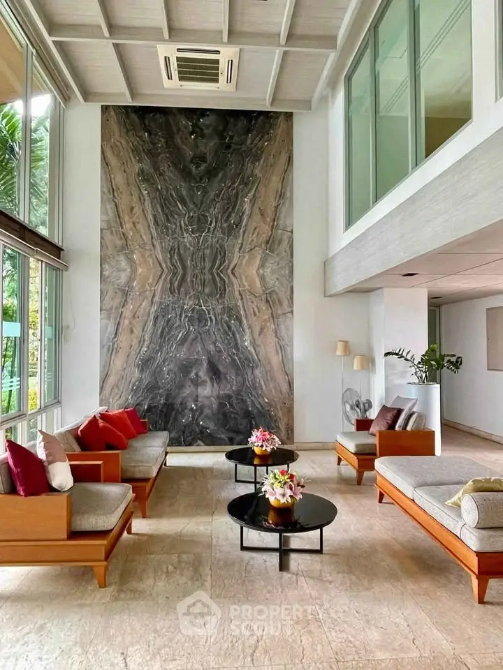 Luxurious living room with high ceilings, elegant decor, and large marble accent wall.