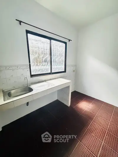 Minimalist kitchen with tiled floor and large window, perfect for natural light.