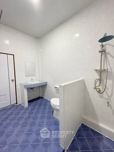 Spacious modern bathroom with blue tiled floor and sleek shower design