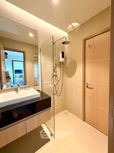 Modern bathroom with glass shower and sleek vanity in contemporary apartment.