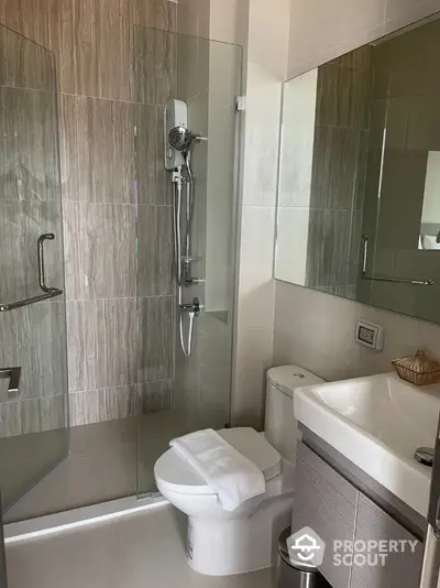 Modern bathroom with glass shower and sleek vanity in contemporary apartment.