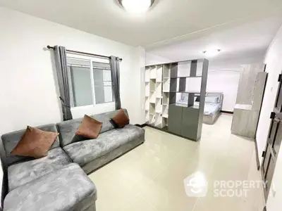 Modern open-plan living room with cozy sectional sofa and stylish partition leading to bedroom.