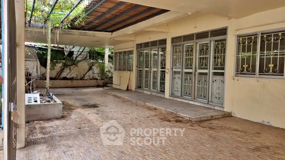 Spacious covered patio with tiled flooring and garden view, perfect for outdoor relaxation.