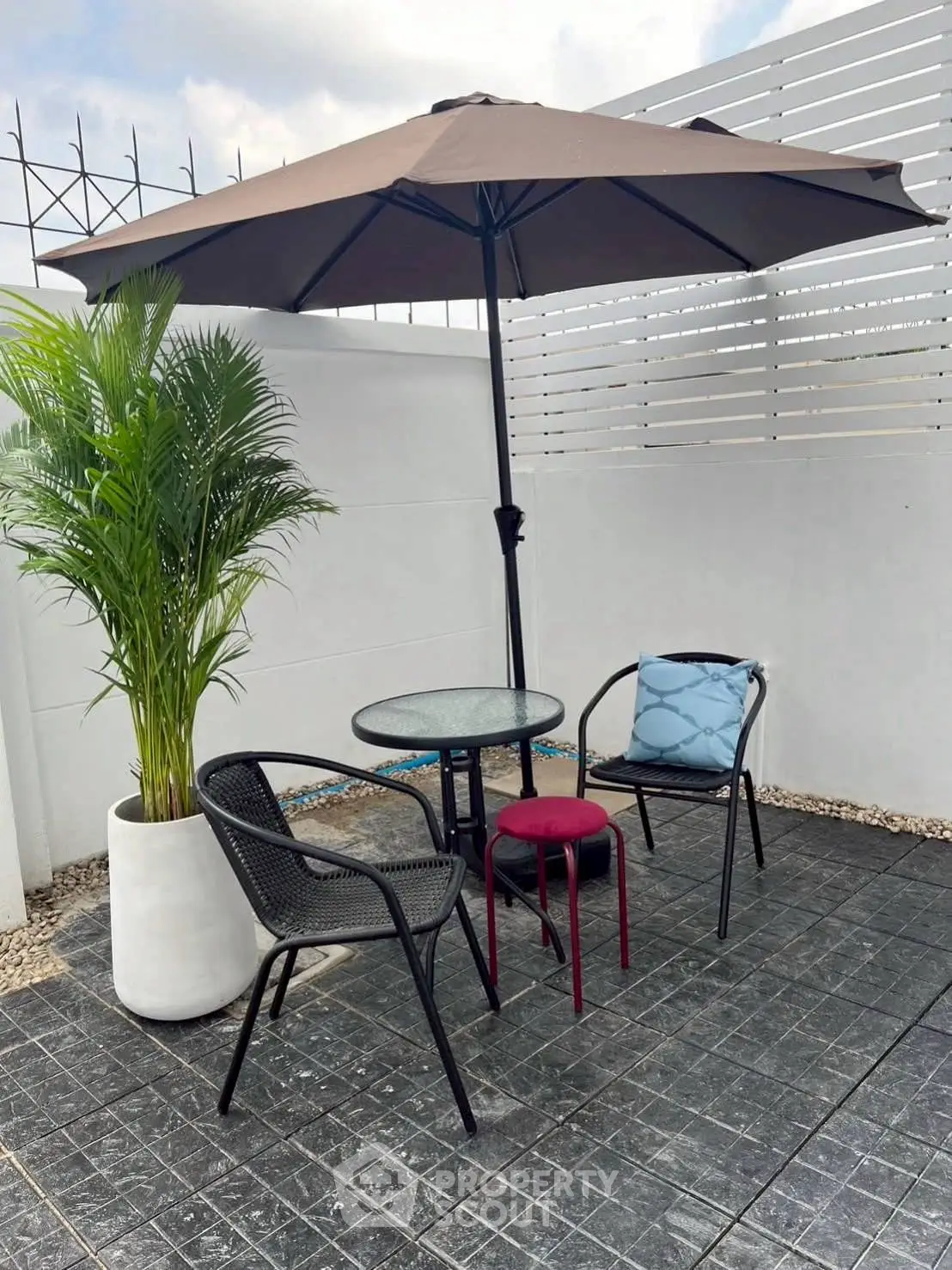 Charming outdoor patio with umbrella, table, and chairs, perfect for relaxation.
