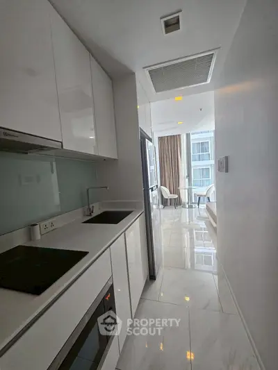 Sleek modern kitchen with glossy white cabinets and built-in appliances in a bright apartment.