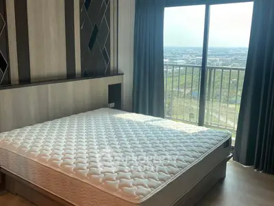 Spacious bedroom with large window offering stunning city view and modern decor.
