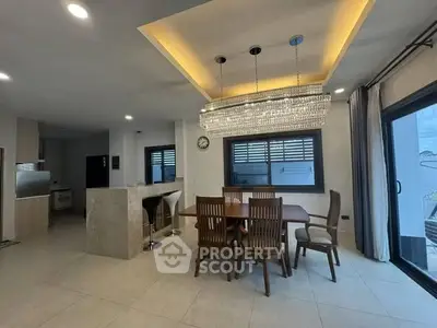 Luxurious dining area with elegant chandelier and modern open kitchen design.