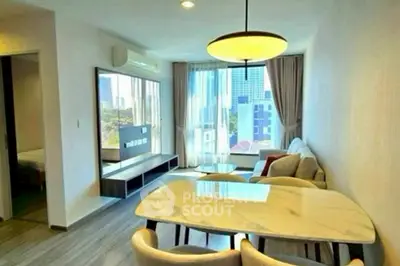 Modern living room with dining area and large window view in urban apartment.