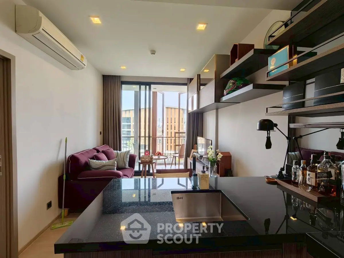 Modern open-plan living room with sleek kitchen and balcony view