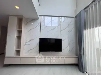 Modern living room with marble accent wall and mounted TV, featuring elegant curtains and sleek cabinetry.