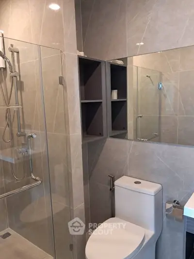 Modern bathroom with glass shower and sleek fixtures in luxury apartment.
