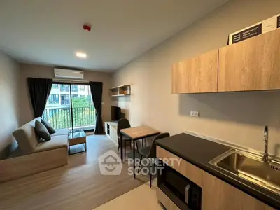 Modern open-layout living room with kitchen, featuring a cozy sofa and balcony view.