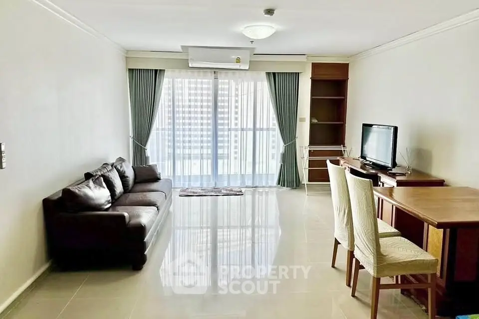 Spacious living room with modern furniture and large windows offering city views.
