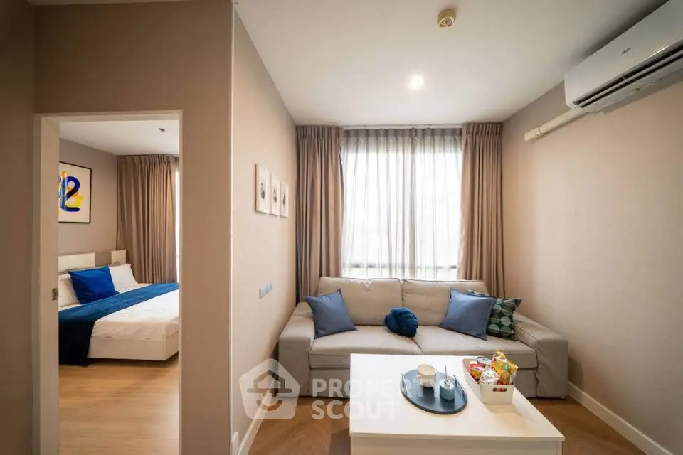 Modern living room with cozy sofa and natural light, adjacent to a stylish bedroom.