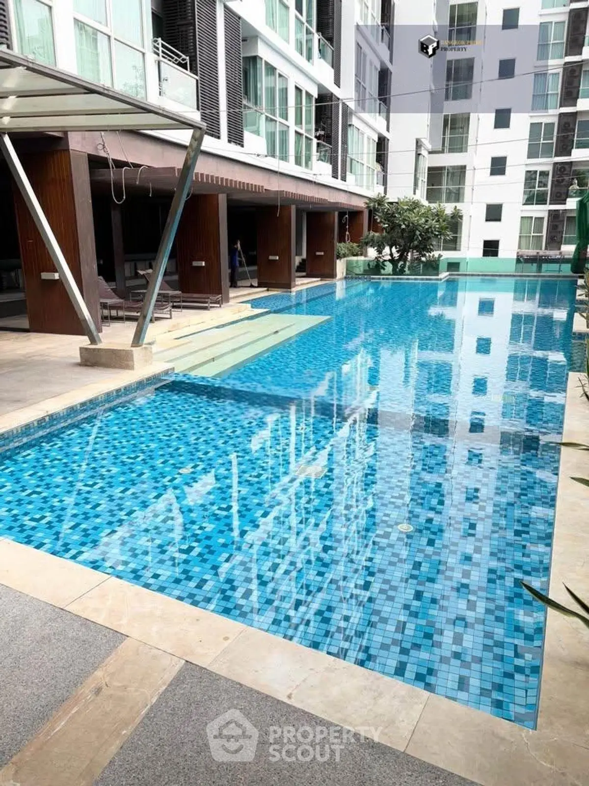 Luxurious condominium pool area with modern design and clear blue water