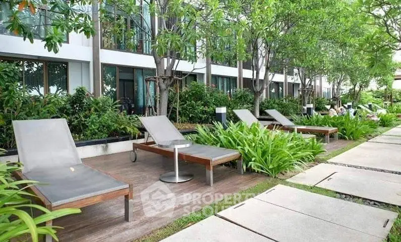 Luxurious garden area with modern sun loungers and lush greenery at a contemporary apartment complex.