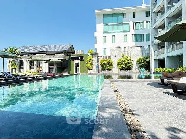 Luxurious poolside view at modern apartment complex with clear blue skies.