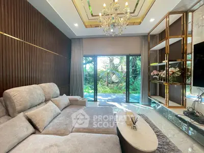 Luxurious living room with plush sofa, chandelier, and garden view through large glass doors.