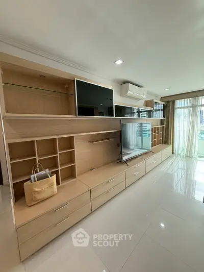 Spacious modern living room with built-in storage and large windows for natural light.
