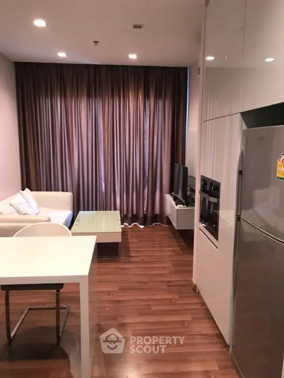Modern living room with sleek kitchen and cozy seating area in stylish apartment.