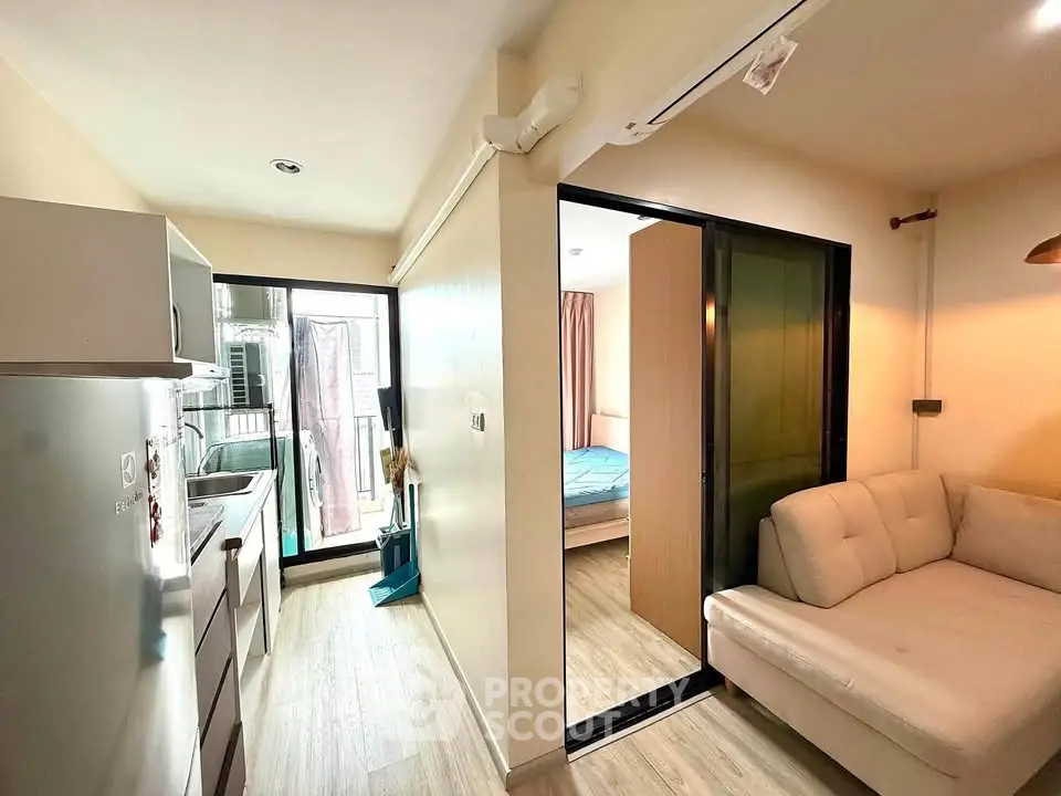 Modern apartment interior with cozy living room and compact kitchen, featuring sliding doors to a bedroom.