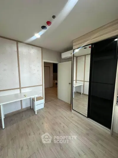 Modern bedroom with sleek mirrored wardrobe and minimalist desk setup.