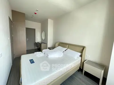 Modern bedroom with minimalist design and neutral tones, featuring a comfortable bed and sleek furniture.