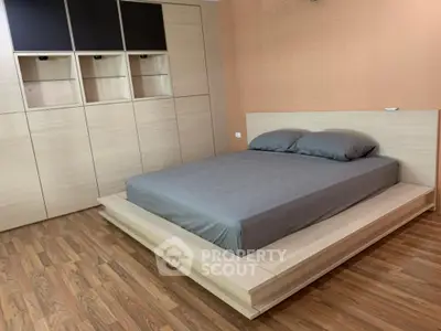 Modern minimalist bedroom with wooden flooring and sleek built-in storage