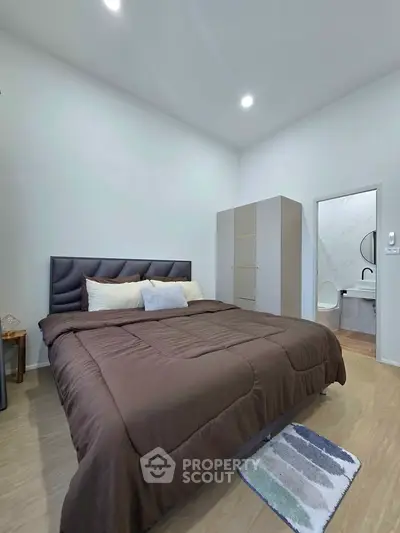 Modern bedroom with cozy bed and ensuite bathroom, featuring sleek design and neutral tones.