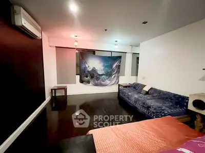Spacious living room with modern decor and unique wall art, featuring a cozy blue sofa and ambient lighting.